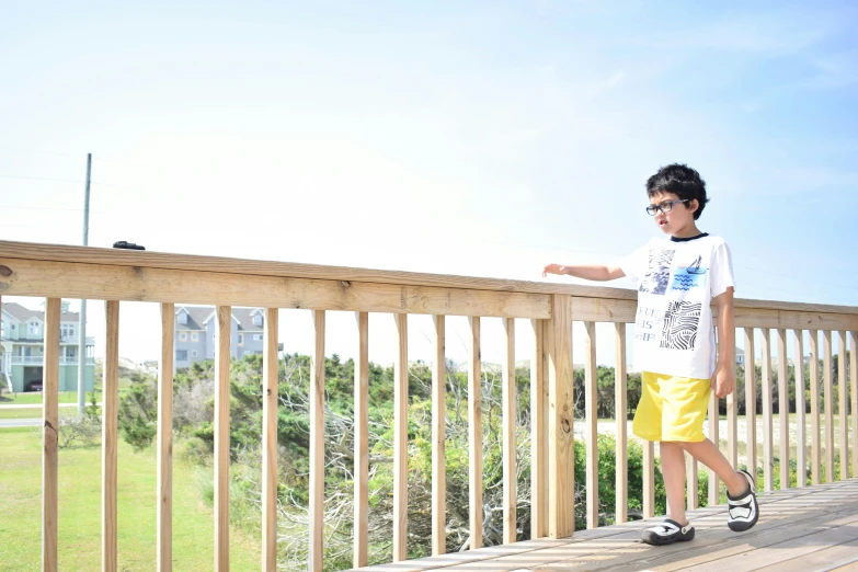 a boy in sunglasses is standing on a balcony