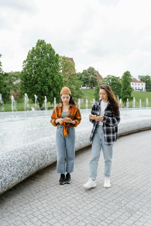 two woman standing next to each other in front of a fountain