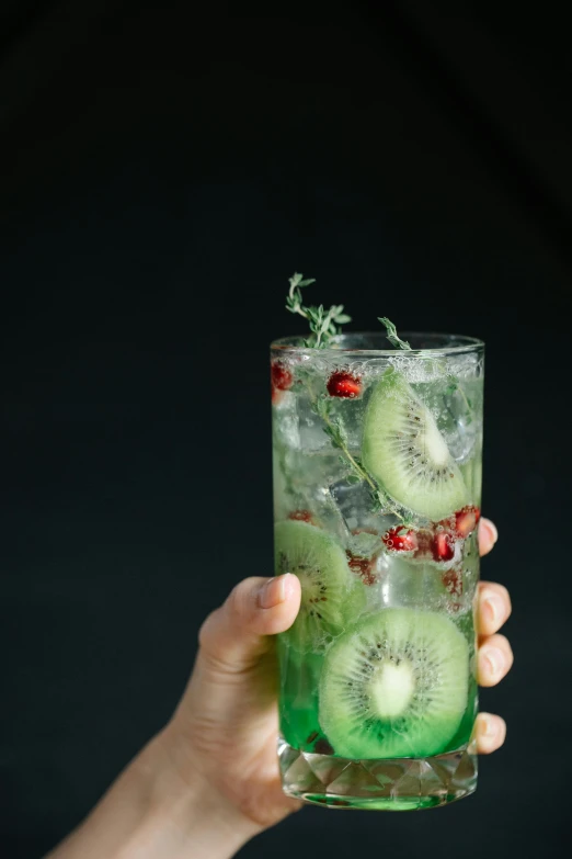 a person holding a glass of kiwi water