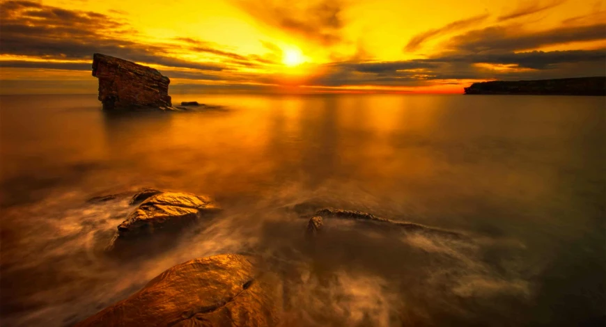 rocks near the water with the sun reflecting on them