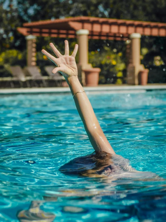 hand reaches for ball while swimming in pool