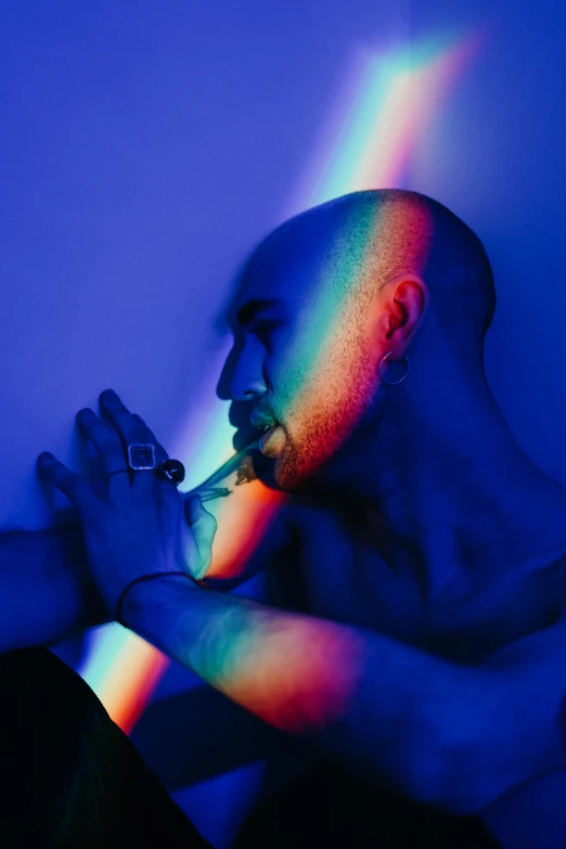 a man in the dark with rainbow light on his face and arm