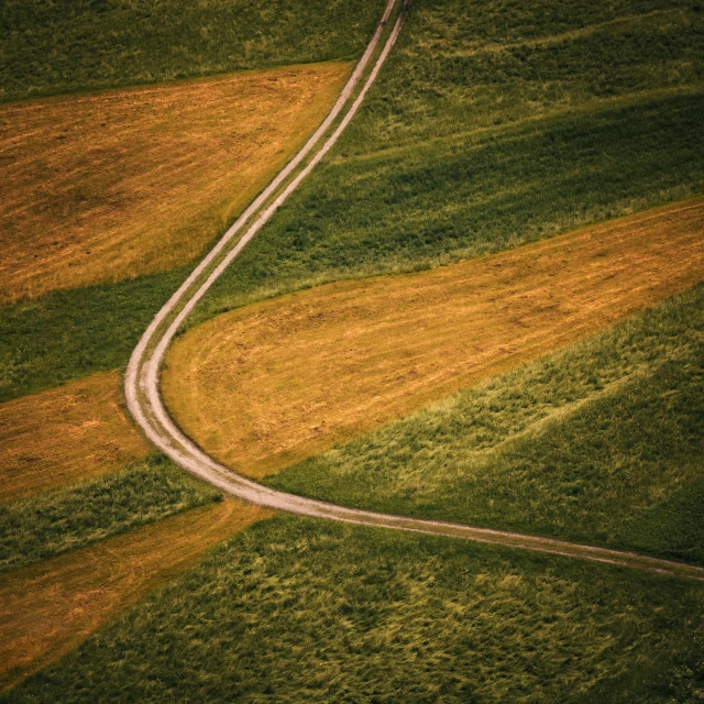 an image of a winding road in the middle of a field