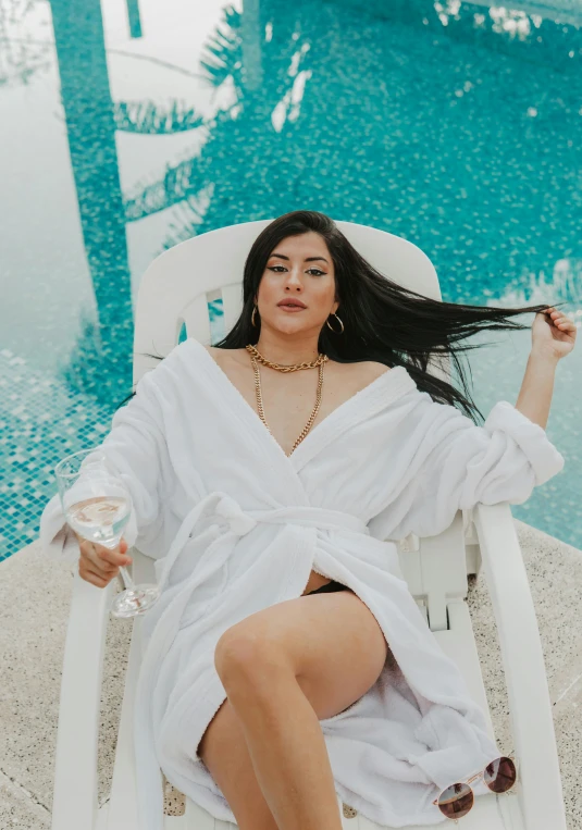 a woman sitting on a beach chair by a pool