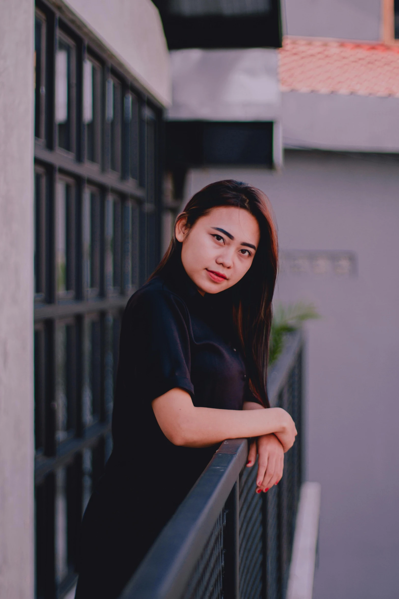 a girl leaning on a railing next to a building