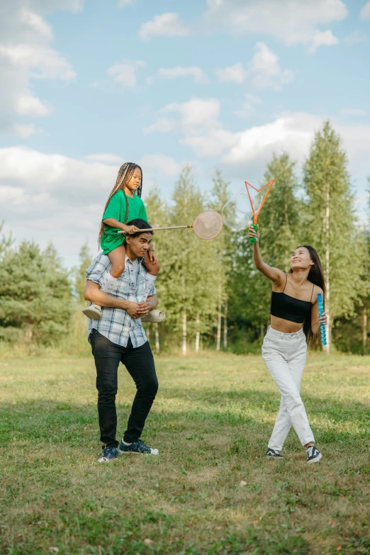 a man holding a  while two other people play in the park