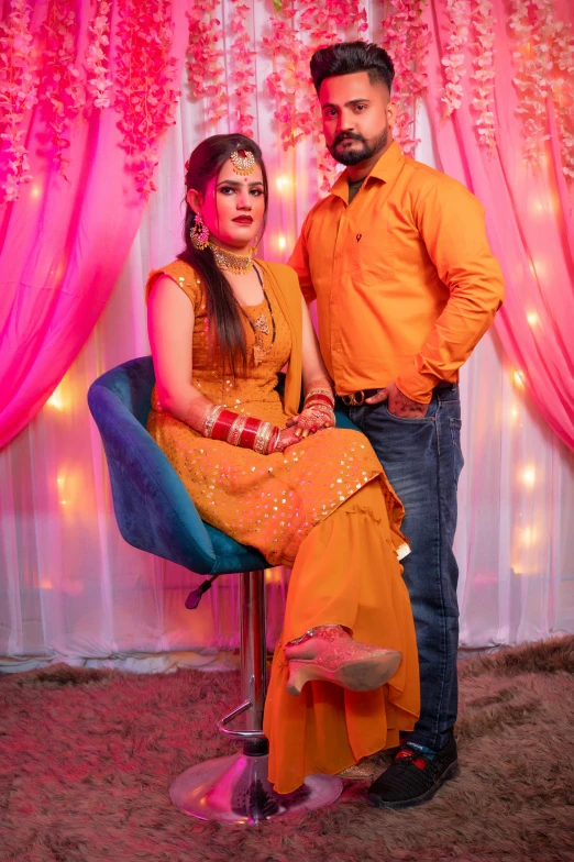 a man and woman posing in front of a backdrop