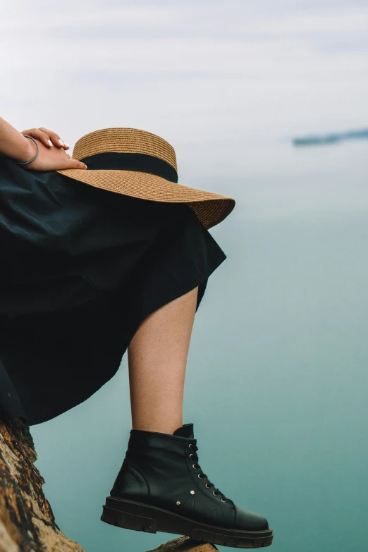 a woman sitting on a rock with a hat on