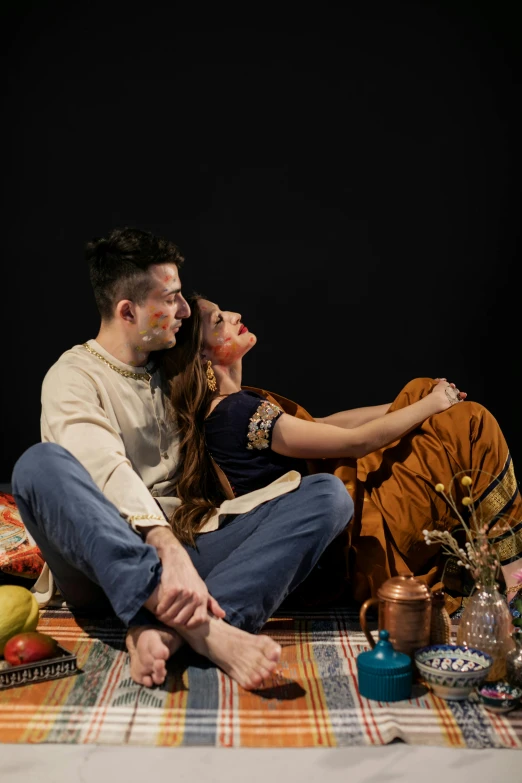 a man and woman are sitting on the floor posing for the camera