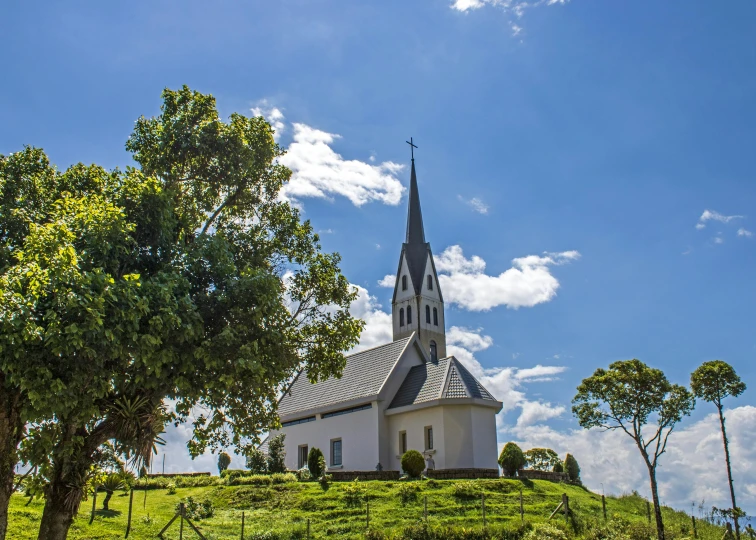 a white church sits on the top of a green hill