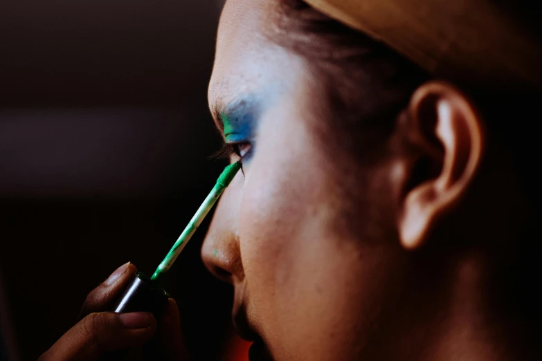 a woman using green makeup to do her eyeshadow