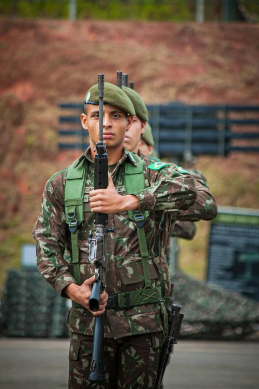 soldiers with guns stand at attention while an officer looks on