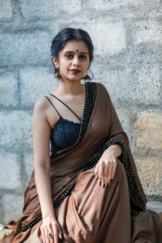 a woman wearing a brown sari with gold jewelry on her neck