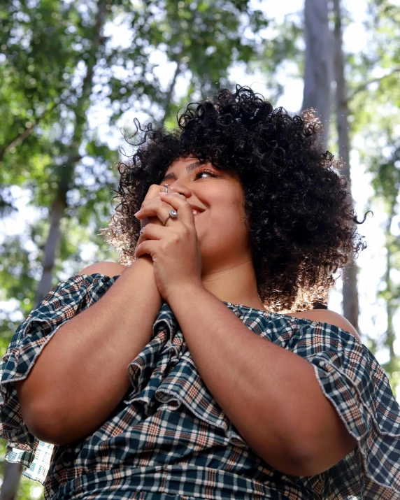 a woman in the forest with her hands together and an expression of emotion