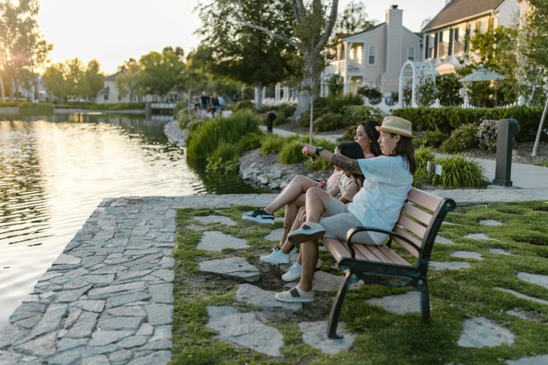 several people sitting on a bench with their backs facing a lake