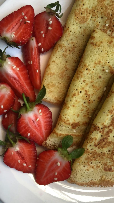 some strawberries and some crepes are laying on a plate