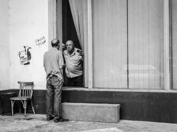 a man looking out of a window while another mans looks in