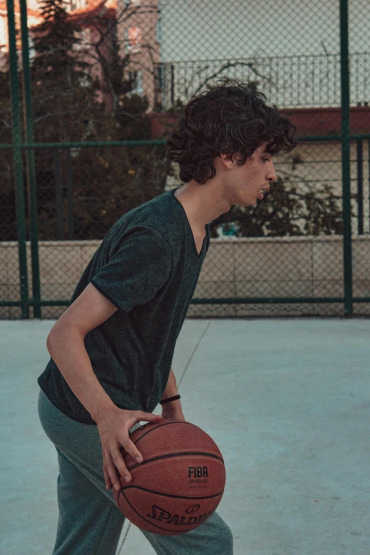 young man on court with basketball with hands in his pockets