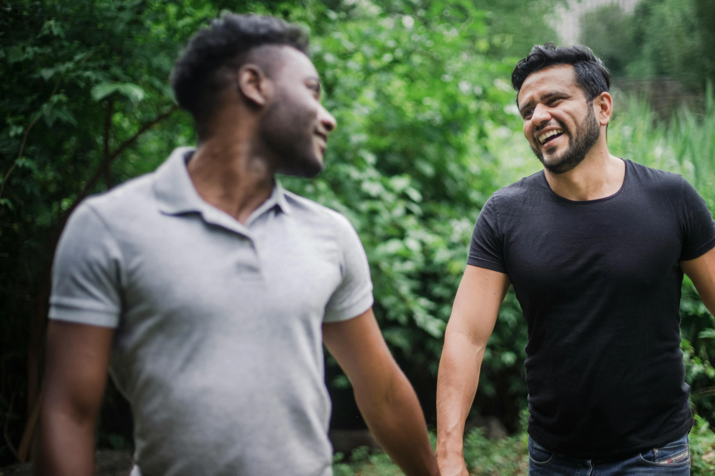 two men walking side by side holding hands and laughing