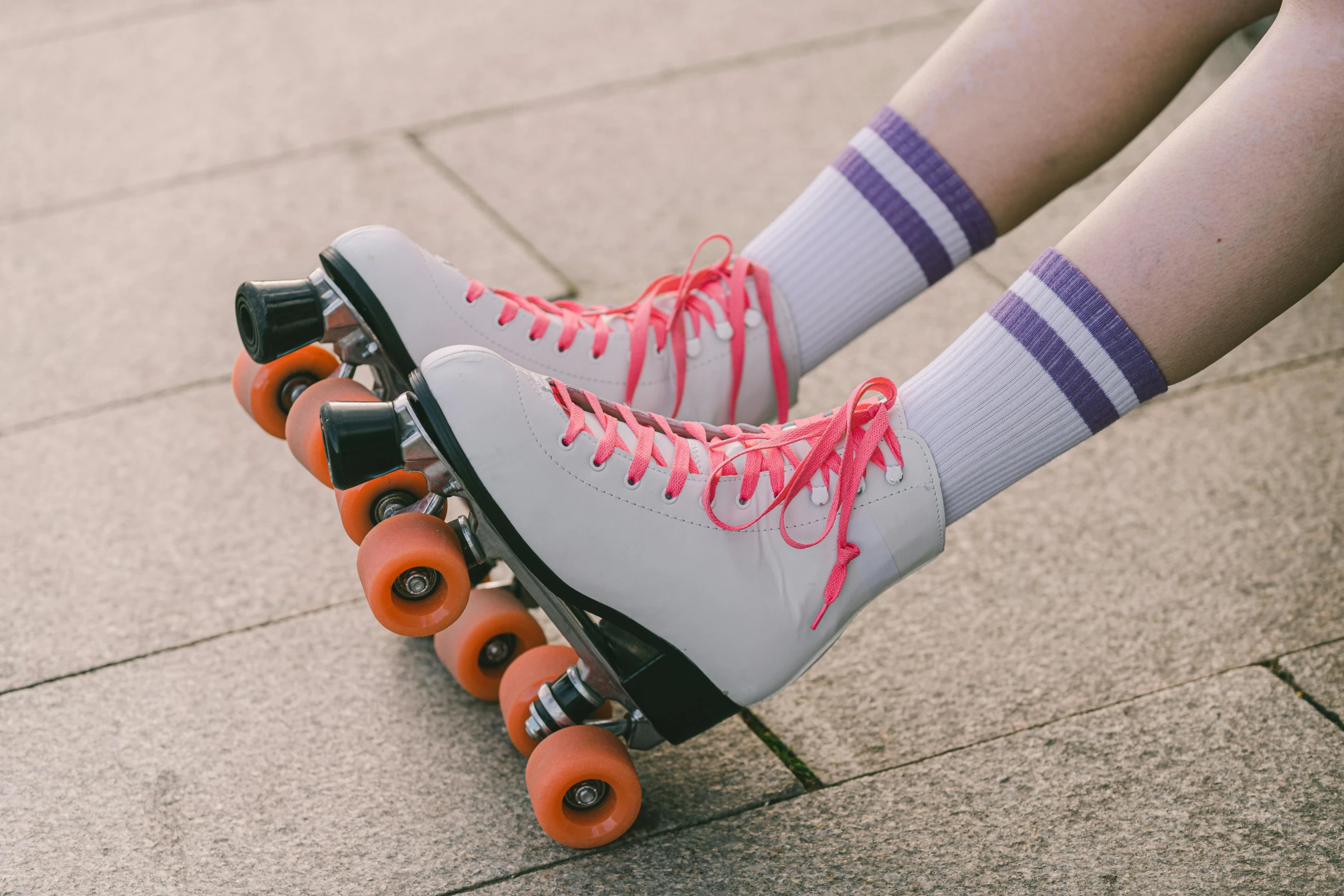 two persons'legs wearing athletic shoes while riding roller skates