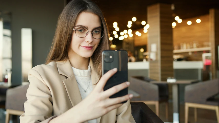 a woman sitting in front of a cell phone holding a smart phone