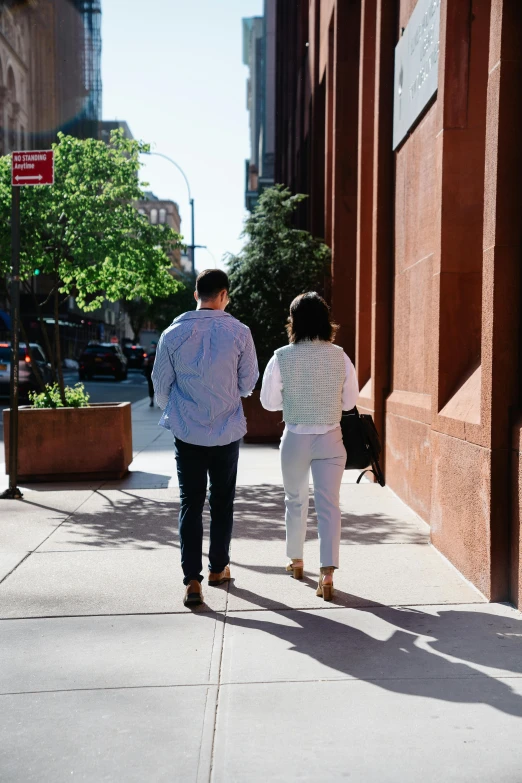 two people walking on a street by a tall building