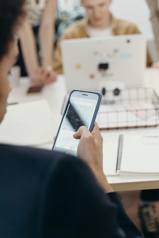 a person on a cell phone and another person working on a laptop