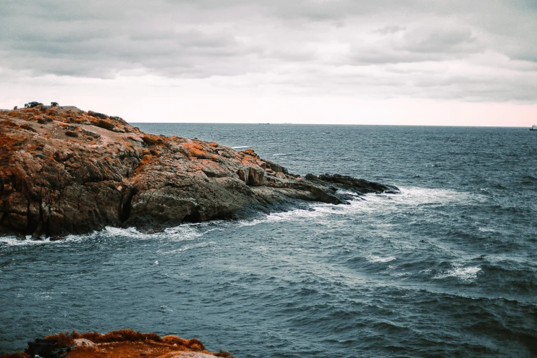 a large rock sticking out of the ocean under cloudy skies