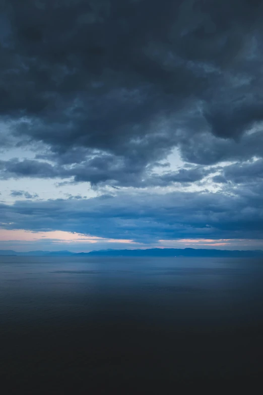 dark clouds loom above the ocean at dusk