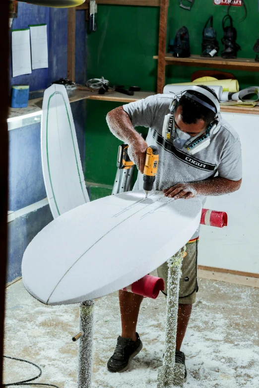 a person sanding a surfboard while working on the back of a truck