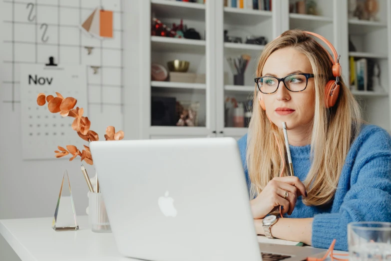 the woman wearing earphones is on her computer