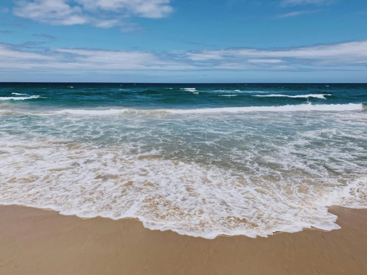 waves come in towards the shore and lay on the sand