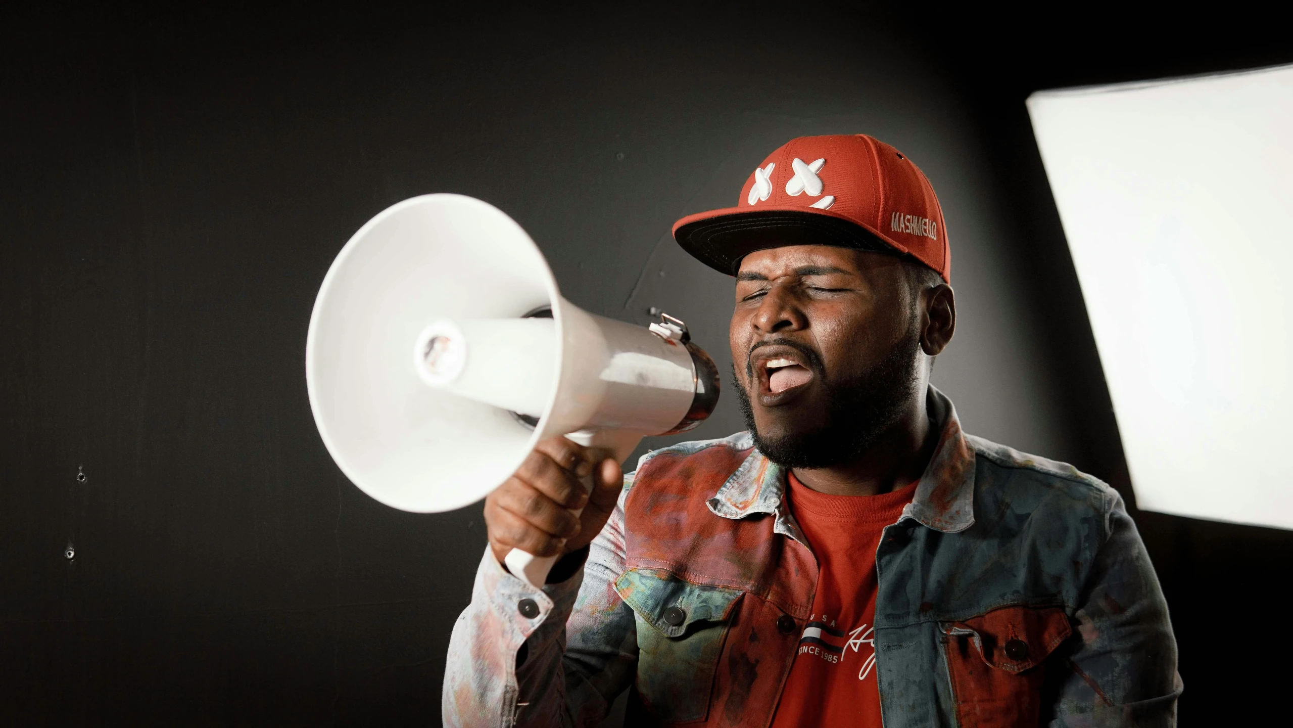 a man holds a white megaphone and a black background