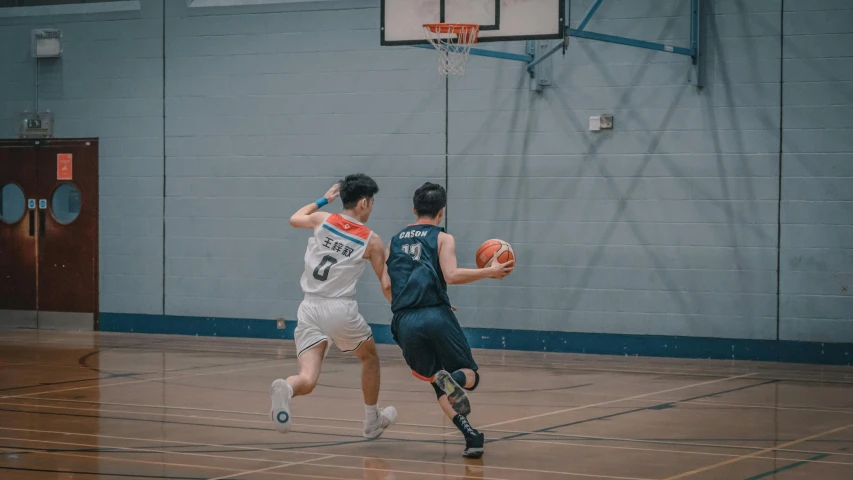 two men playing basketball on an indoor court