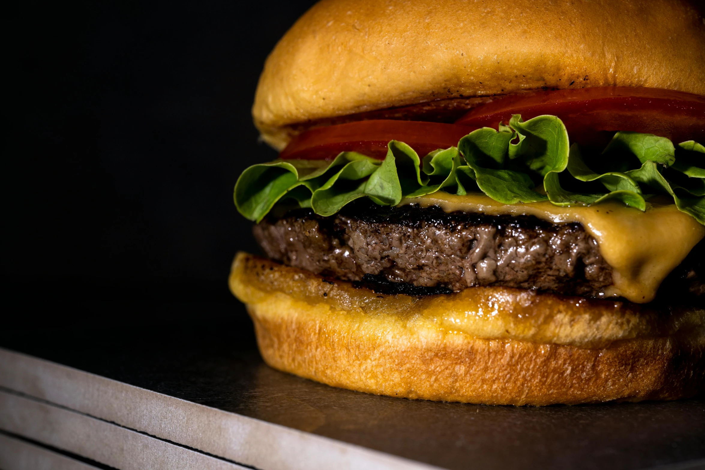 a burger with some meat, cheese and tomato slices