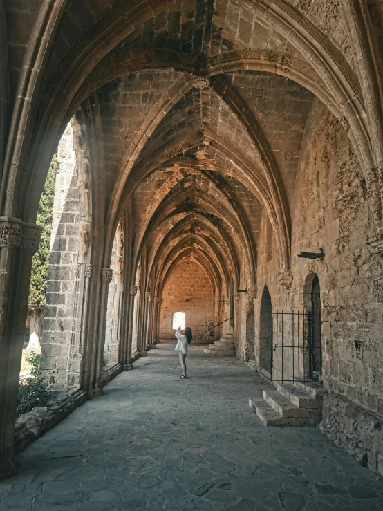 man walking in the dark passage between two arched buildings