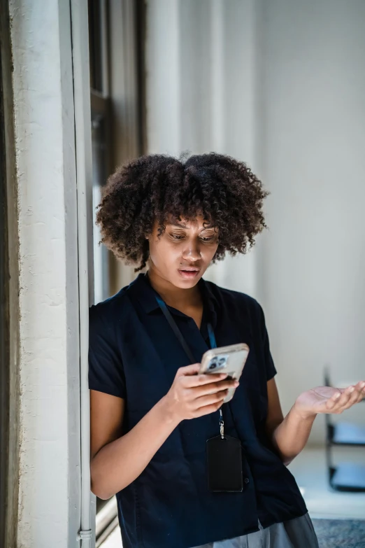 a woman standing in front of a wall using a cell phone