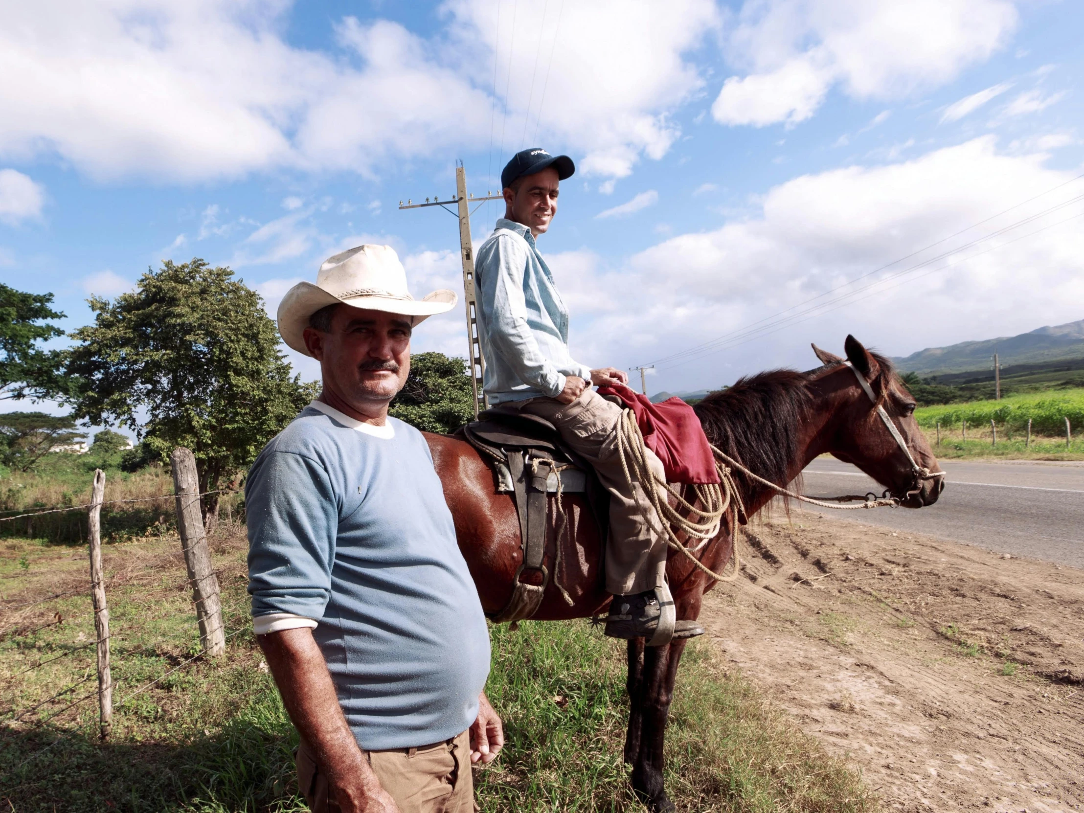 a man standing on the side of a dirt road with a woman