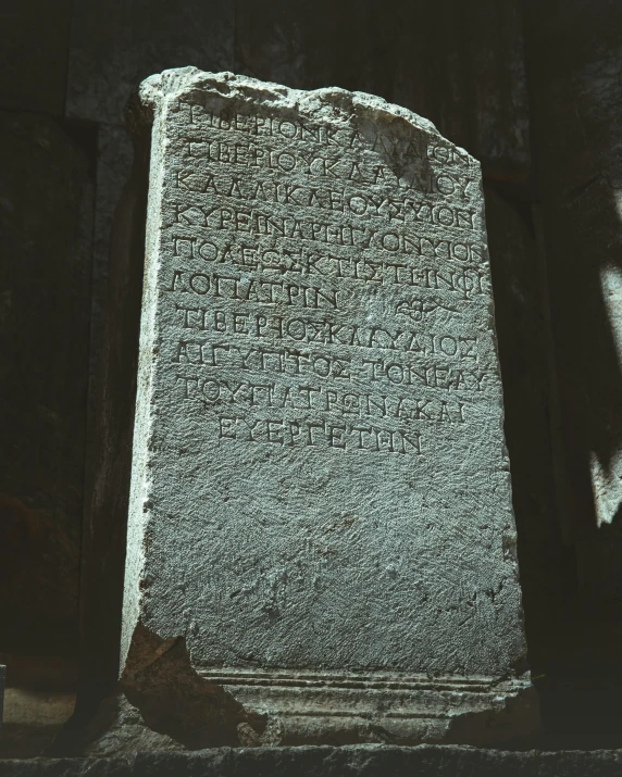 a stone slab covered in writing next to a wall