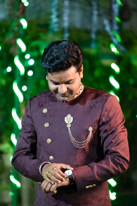 man in maroon outfit using a cell phone with a green and white background