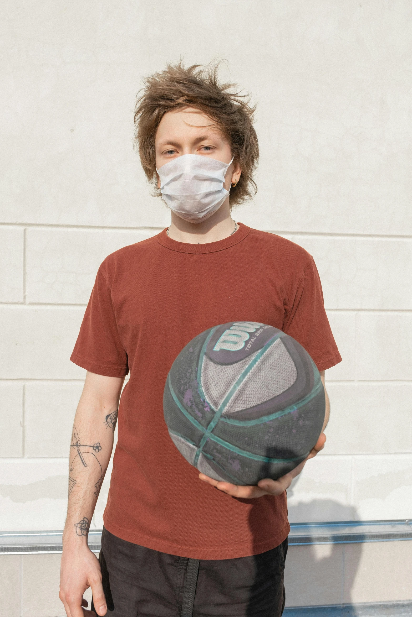 a young man wearing a face mask and holding a basketball