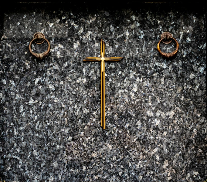 a metal cross on the ground with two ring decorations