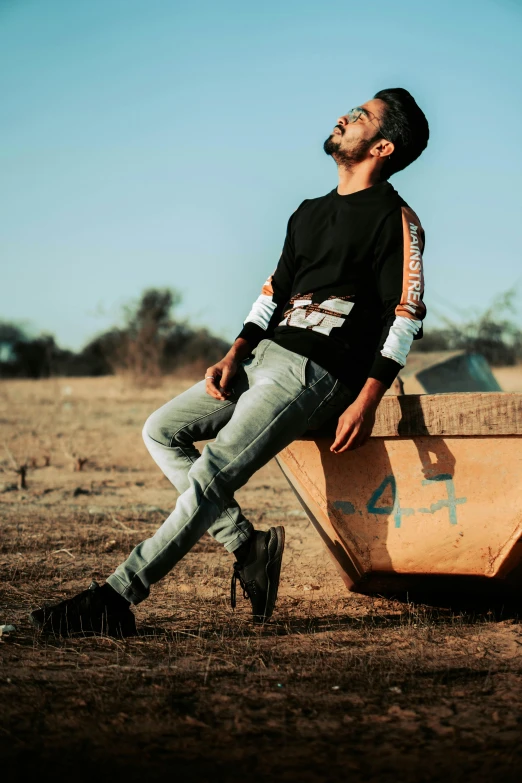 a man sitting on a wheelbarrow in an abandoned field