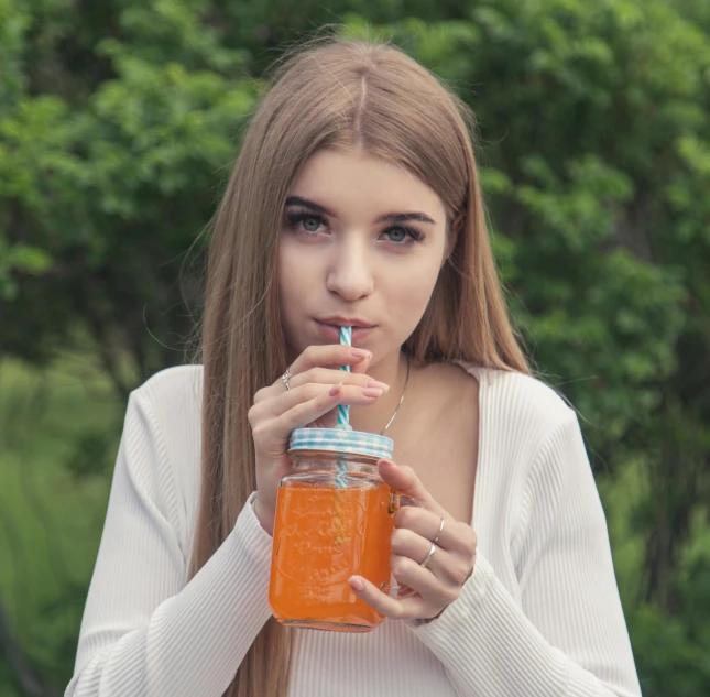 the young woman drinks out of a mason jar