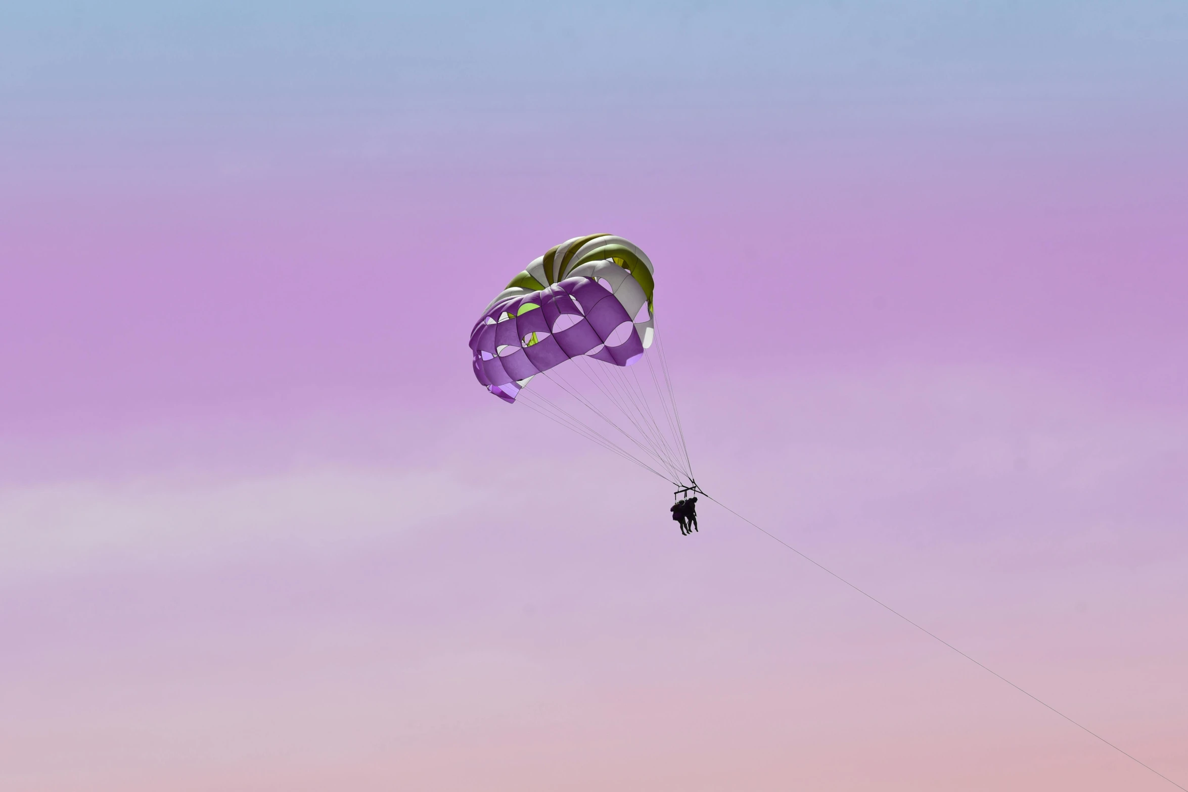 two parachutes are flying on a pink and blue sky