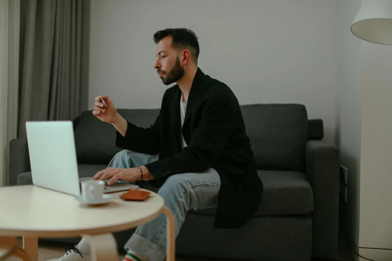 a man sitting on a couch with his laptop in front of him