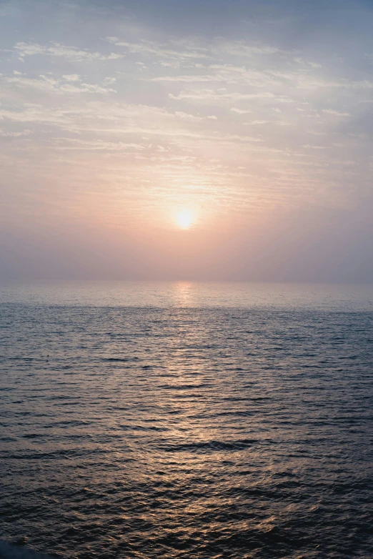 a beach with water and sun rising on the horizon