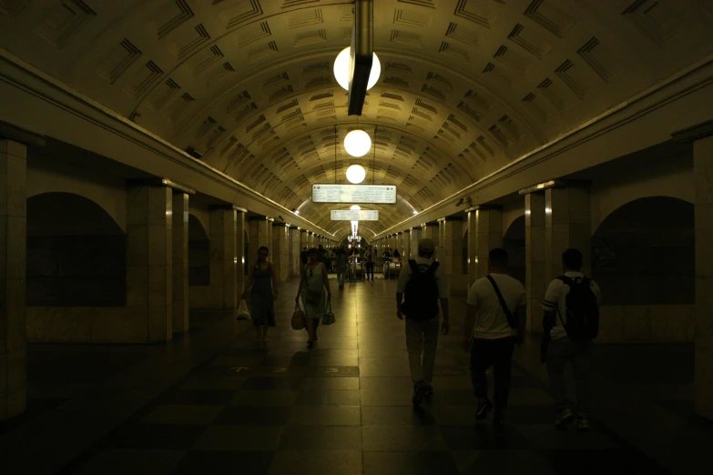 people are walking down a train tunnel in the dark