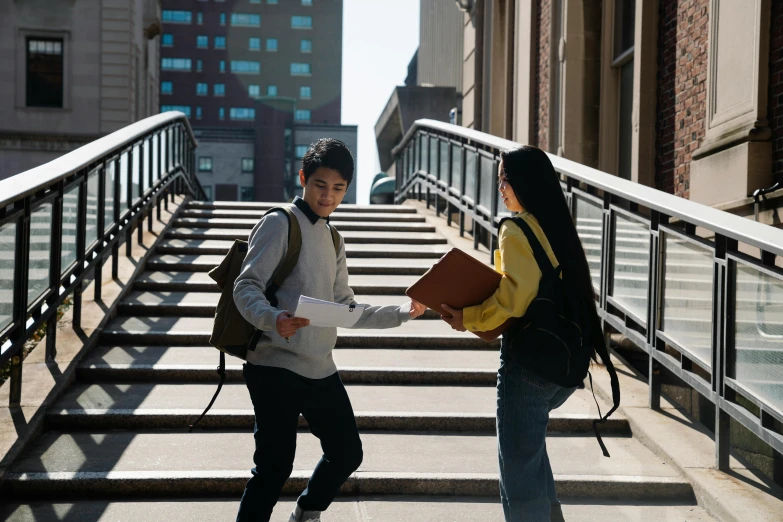 two women are talking on the stairs in front of the building