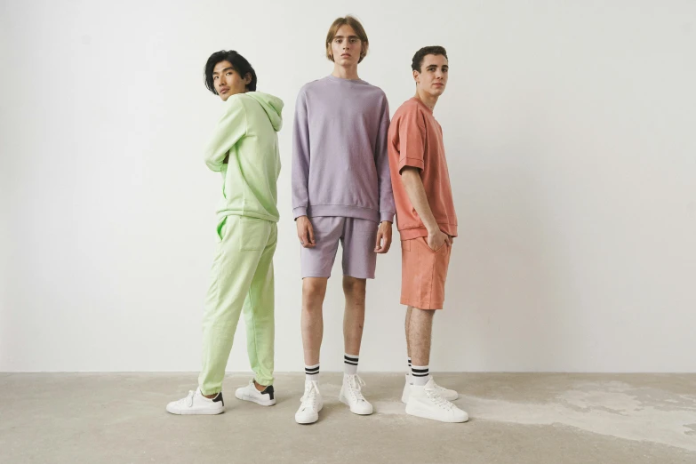 three men stand in different clothes on white background